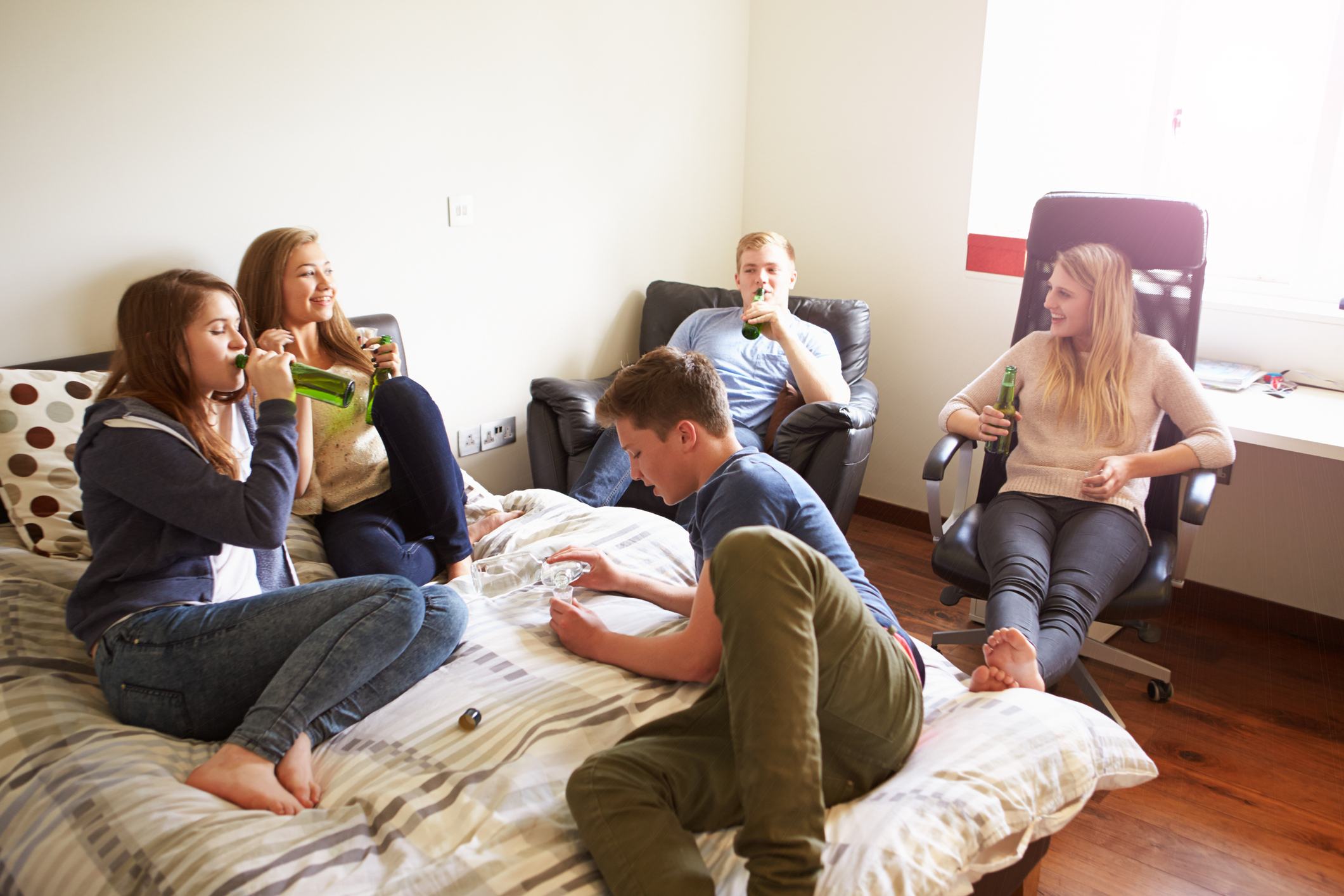 Group Of Teenagers Drinking Alcohol In Bedroom.