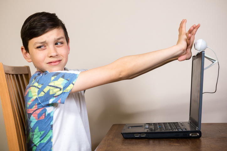 Young boy blocking a webcam because of cyberbullying.