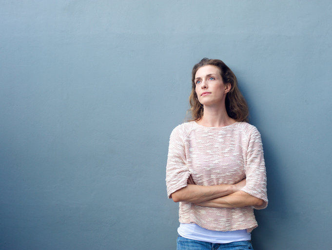 Portrait of an attractive woman posing with arms crossed looking away with emotionally numb expression